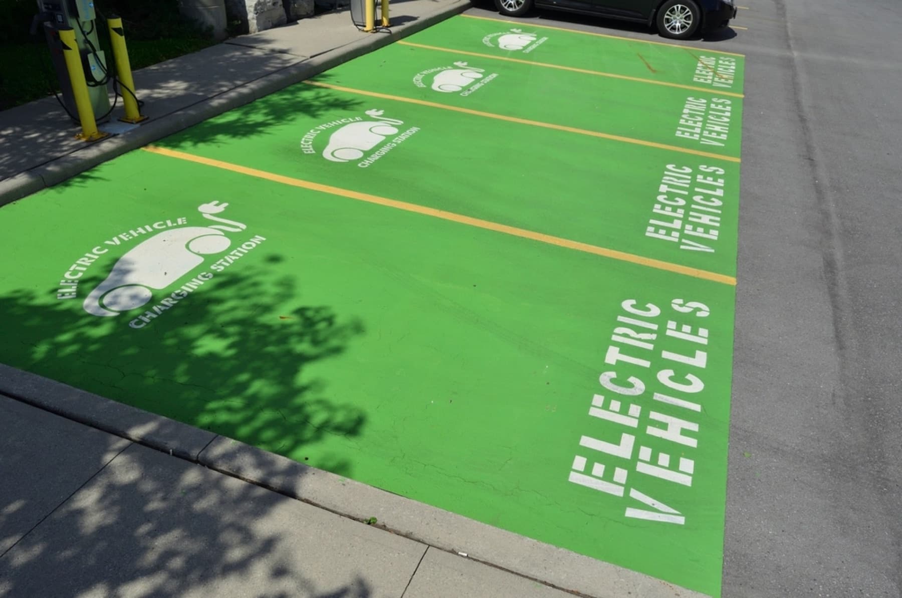 Parking bays painted green and marked for electric vehicles, each with a charger.